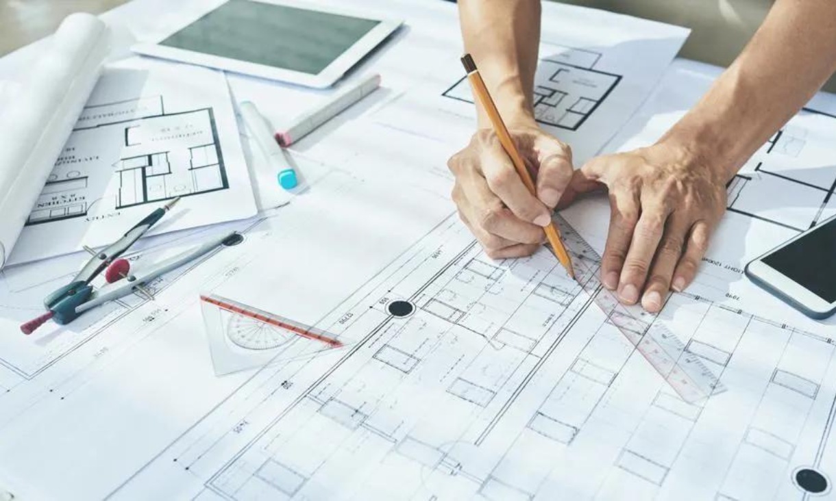 Person using ruler to draw on construction plans