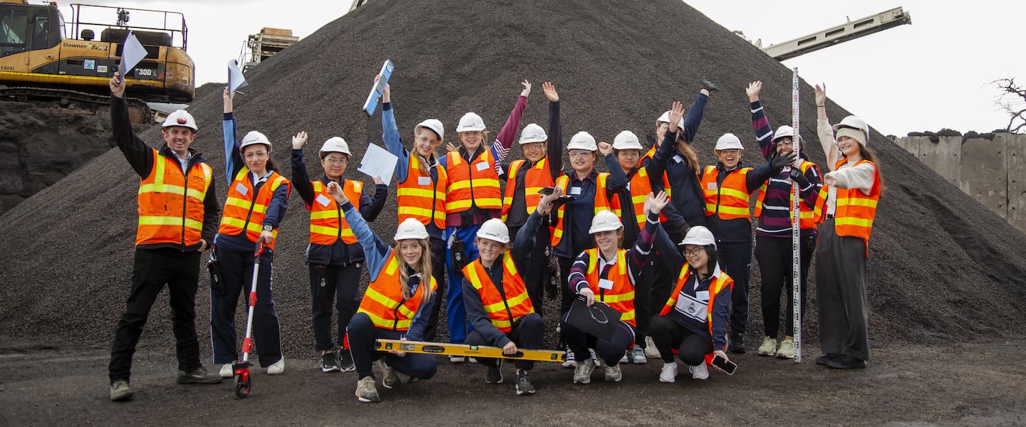 big group photo of smiling female high school students and staff outside on excursion at asphalt plant