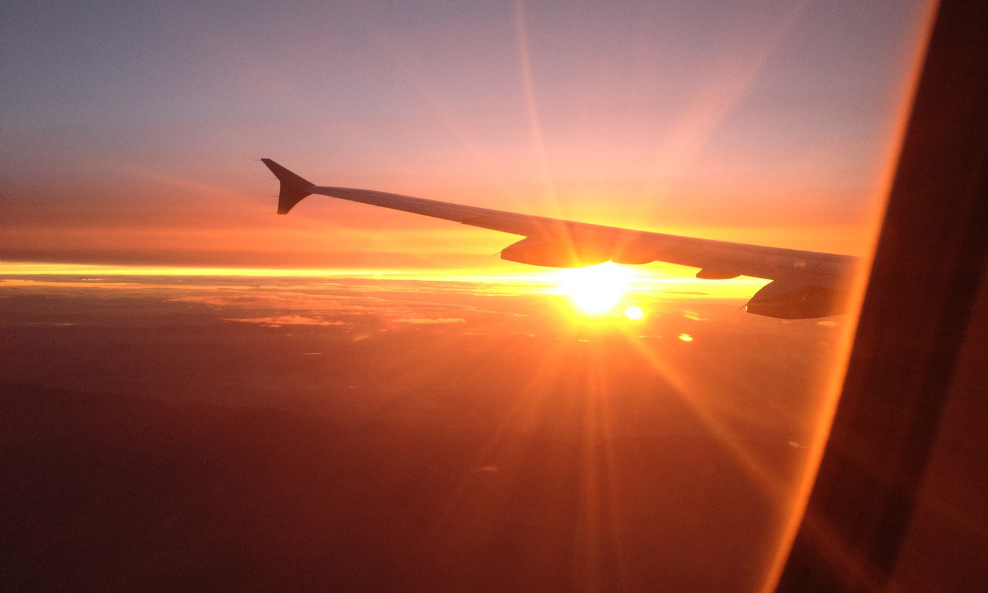 Plane wing in the sky at sunset