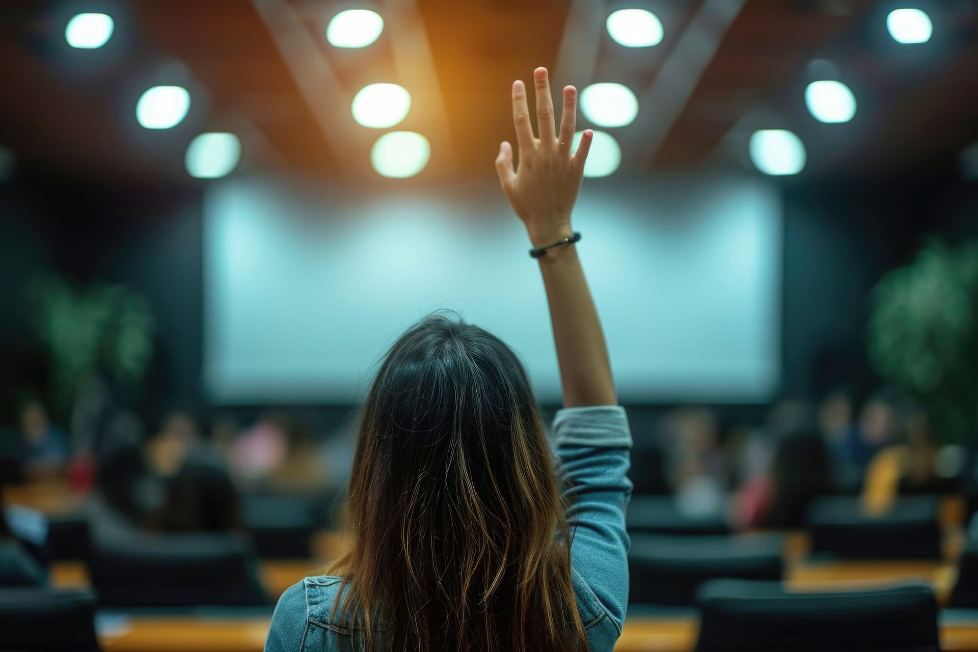Person with hand raised in an auditorium