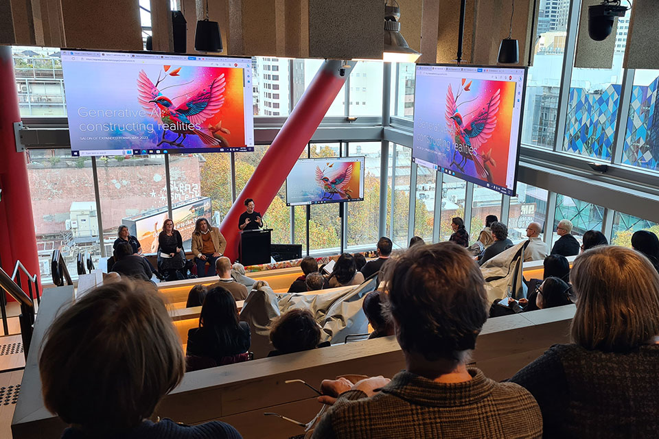 People giving a talk with brightly coloured screens behind them