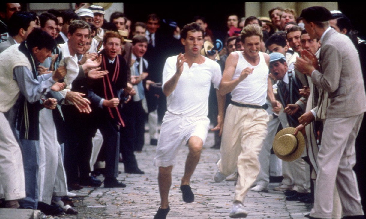 Two men running a race with a crowd cheering them