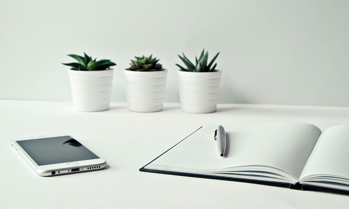 A notebook, pen and a mobile on a table