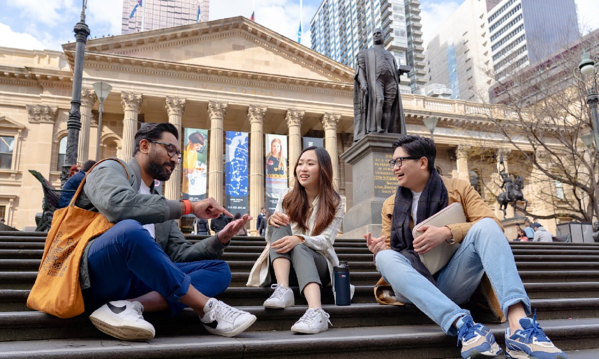 students seated on the State Library of Victoria steps, facing each other in conversation