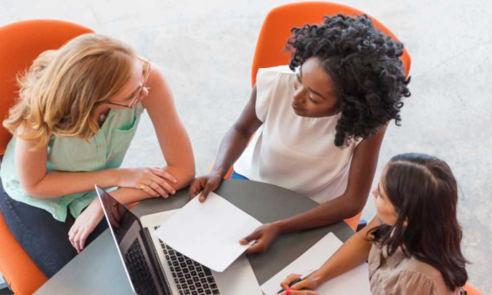 Three people sitting around laptop