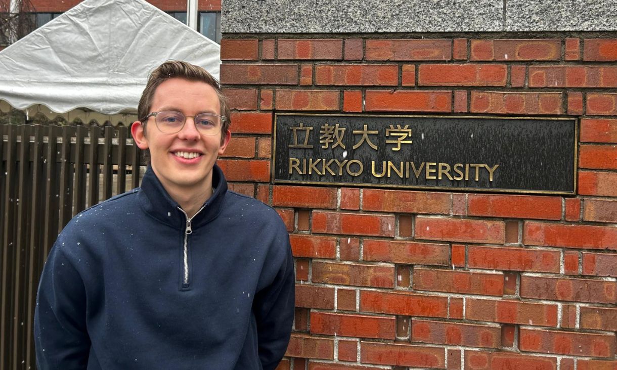 Max standing next to the sign for Rikkyo University, a light snow falling.