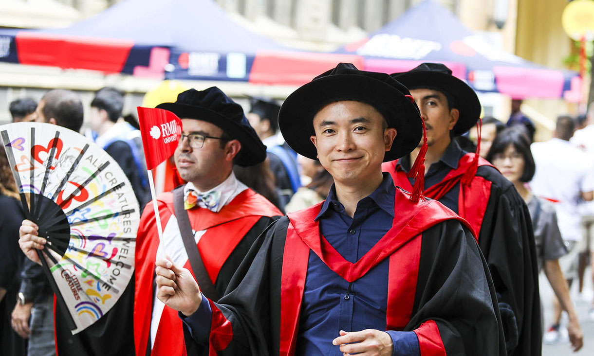 Male PhD graduate smiles at the camera during the 2023 Graduation Parade
