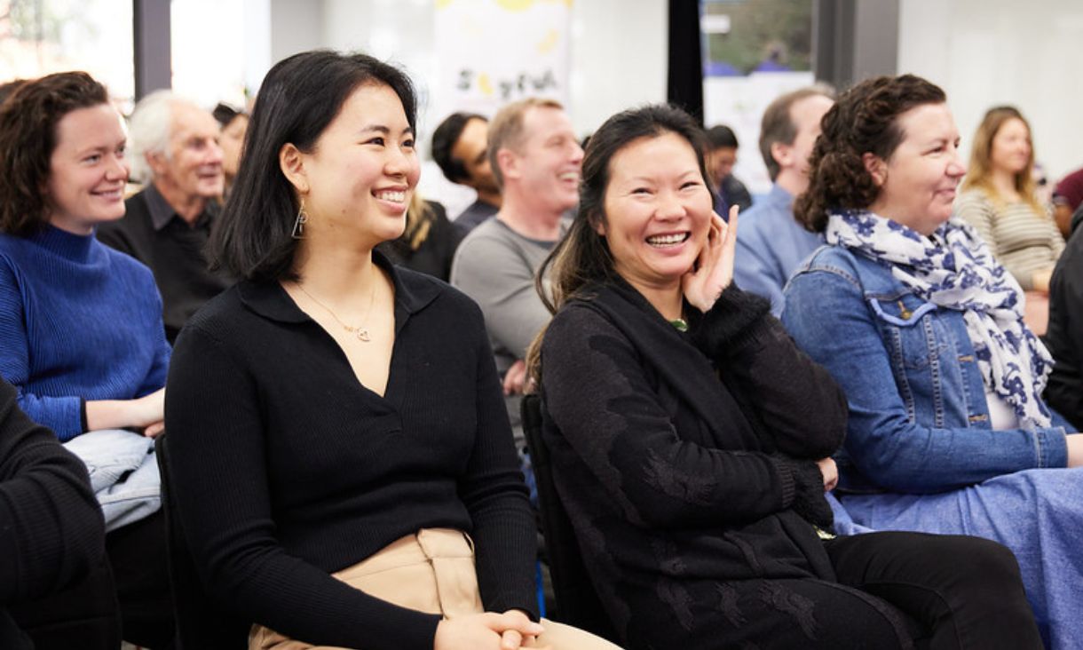 People laughing while sitting in audience of presentation