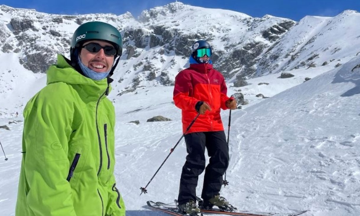 Two people in snow gear on a ski slope.