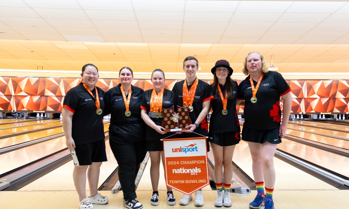 Six people win black uniforms stand in front of a bowling alley.