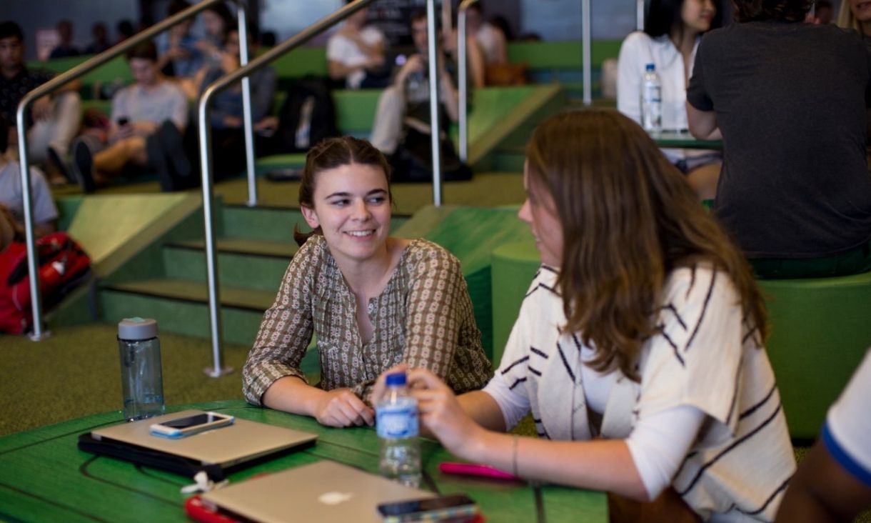 A student sitting with a peer mentor in a shared space on campus.