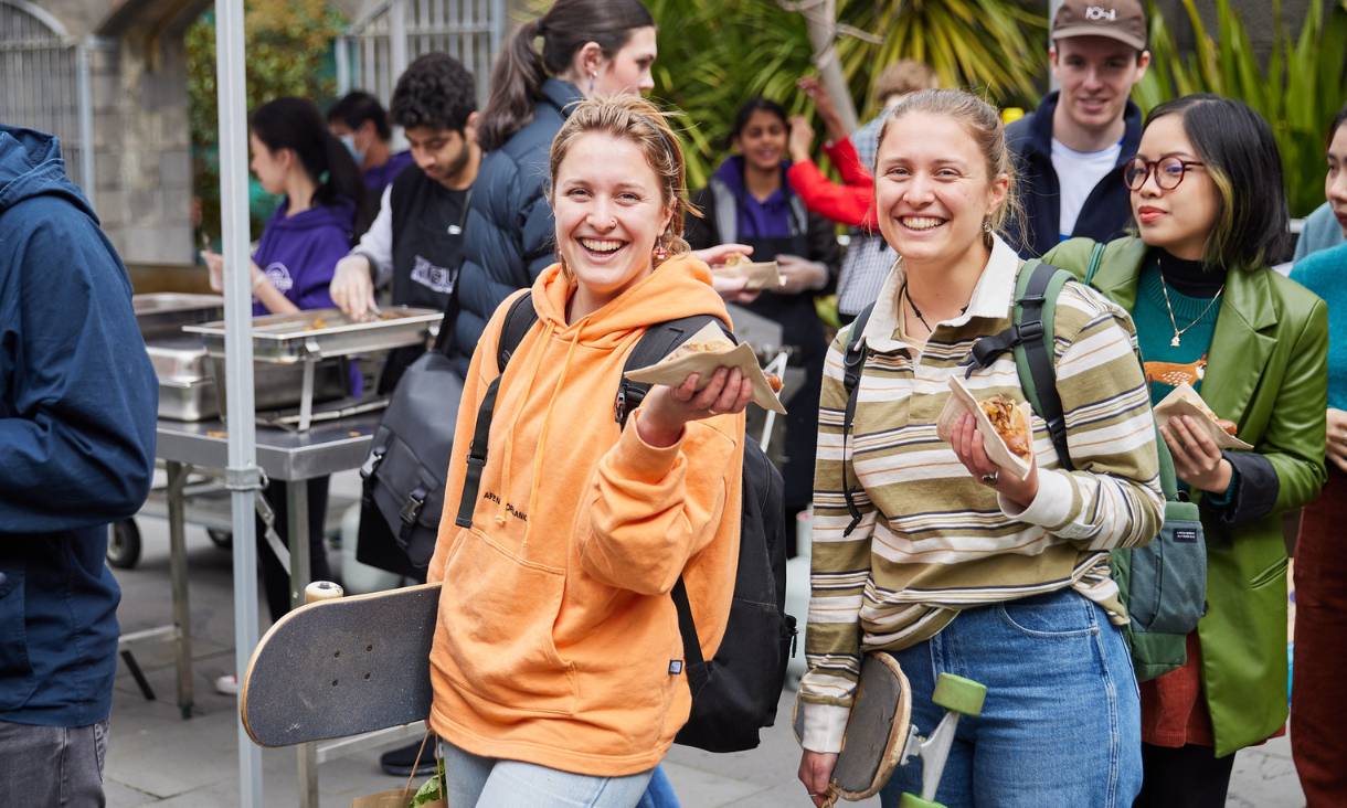 Two students smiling and holding vegan sausages