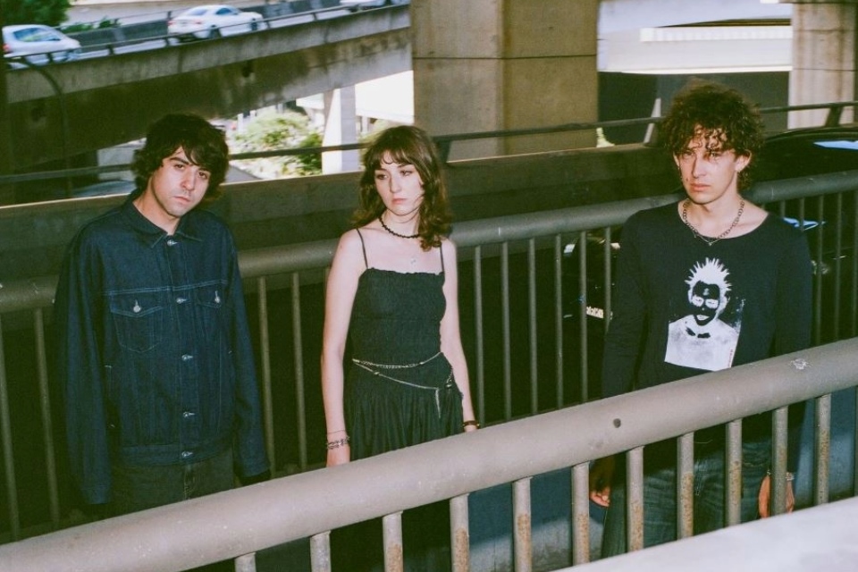 Three people stand on a bridge during a photoshoot.