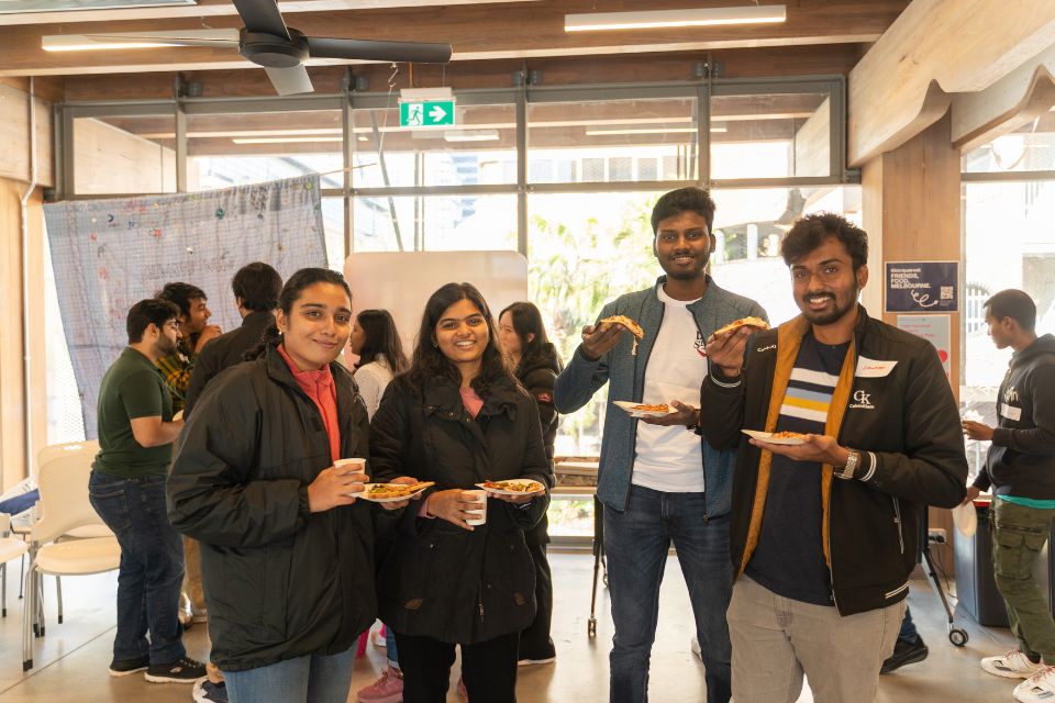 A group of students holding up pizza. 