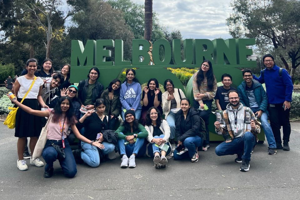 A group of students posing in front of a sign that reads 'Melbourne'.