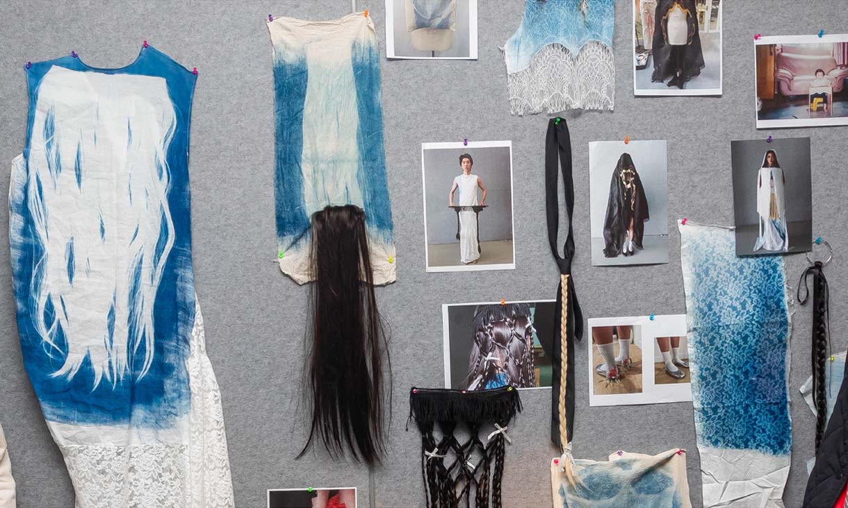 A pin board with a series of blue and white fabrics, hair extensions, and images of models wearing various clothing.