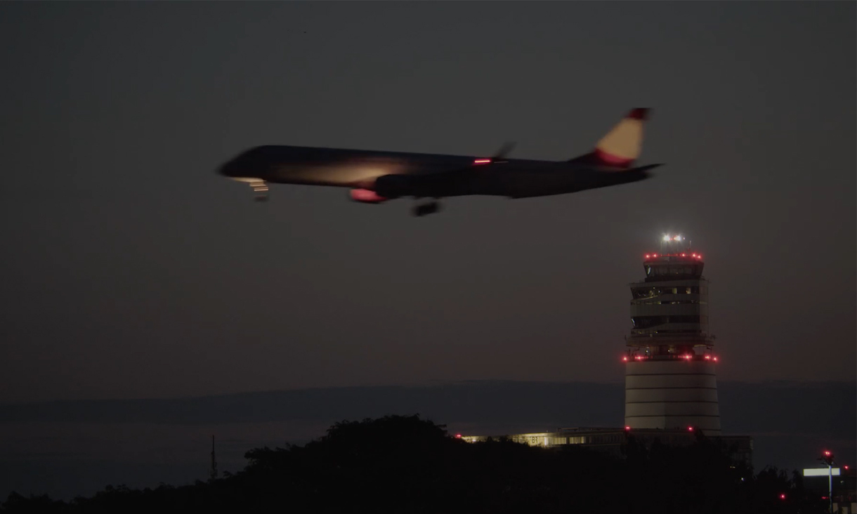 A plane flies past an air traffic control tower.