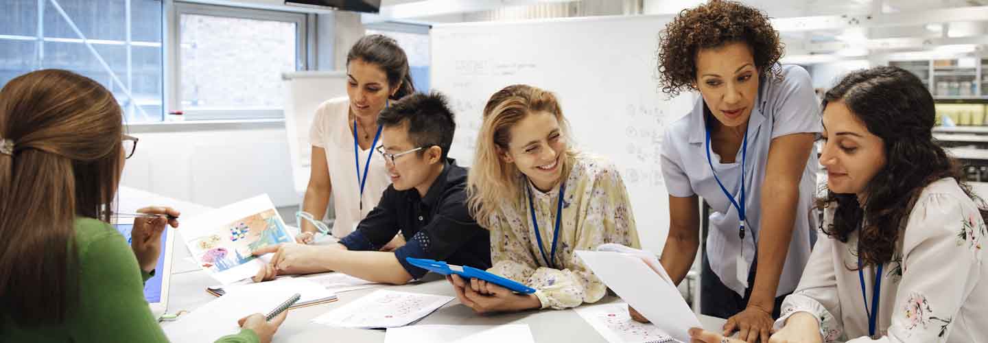 A group of six people looking at brochures in front of a whiteboard.