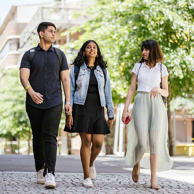 Three students walking on a street in the RMIT Melbourne city campus.