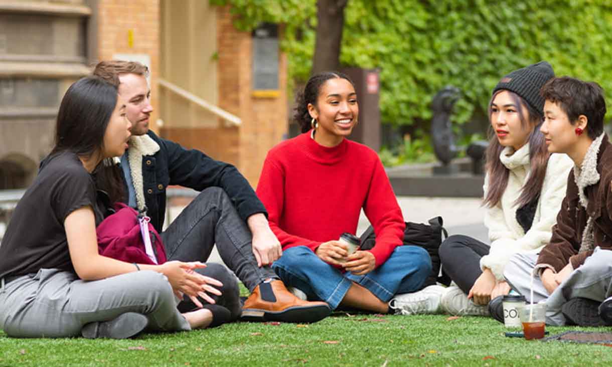 A group of five students sitting on the lawn in Bowen Street at the RMIT Melbourne city campus.