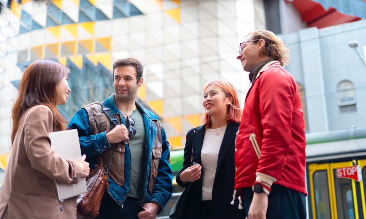 Group of students smiling in a group in front of RMIT buildings