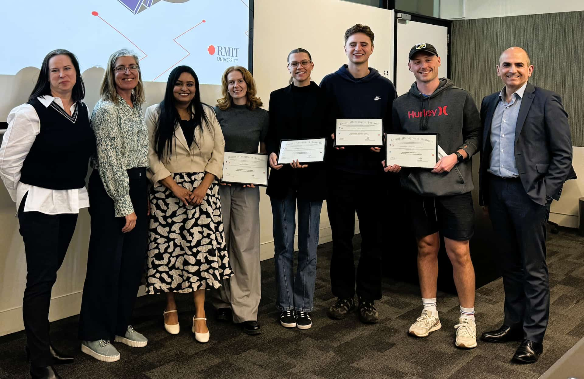 Group of eight people, some holding certificates