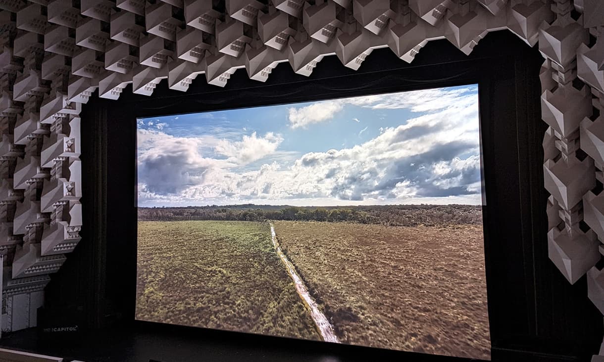 a screen with an image of a road with baron land either side of it and cloudy blue skies above