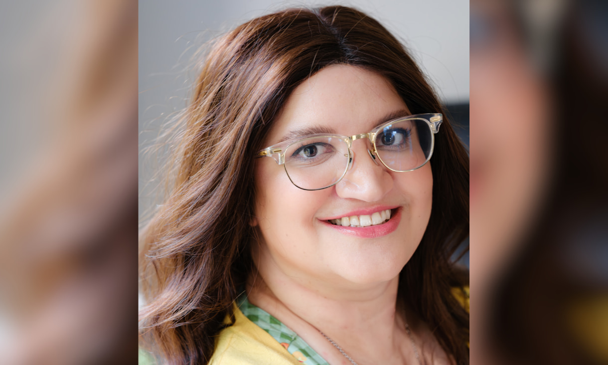 Lady wearing glasses in front of a grey backdrop