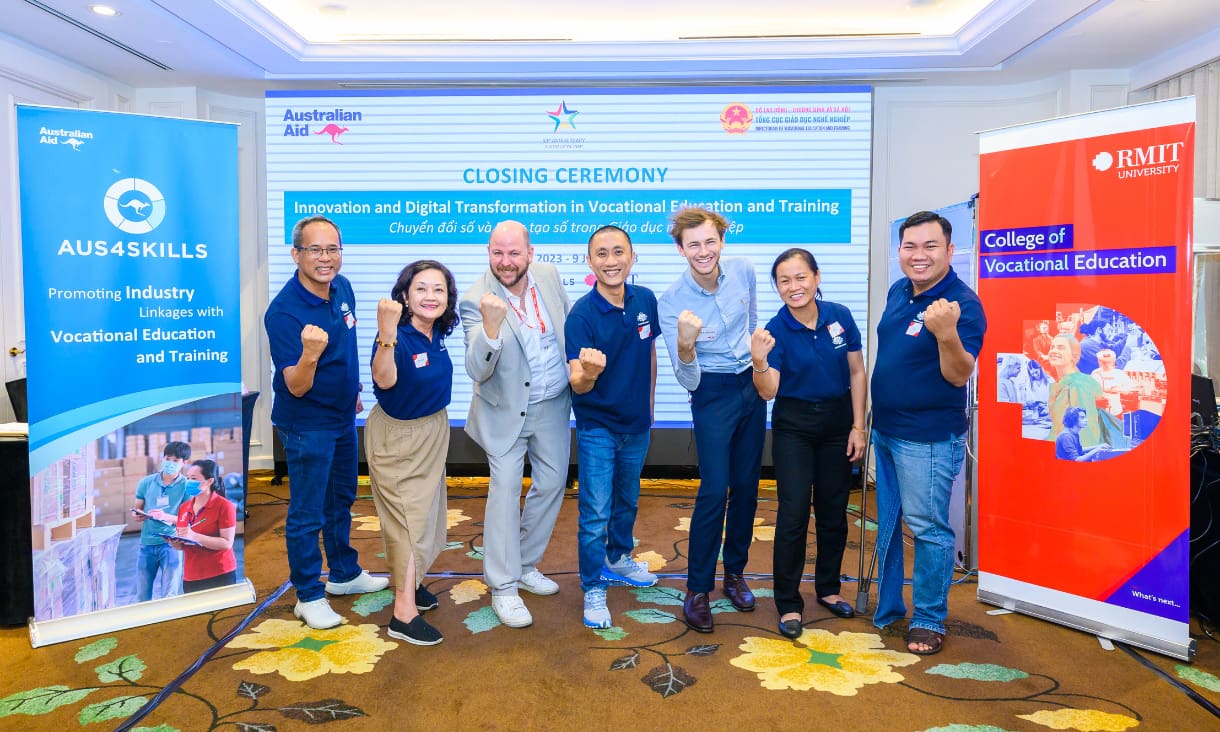 seven people stand in front of a sign reading 'closing ceremony', clenching their fists in victory