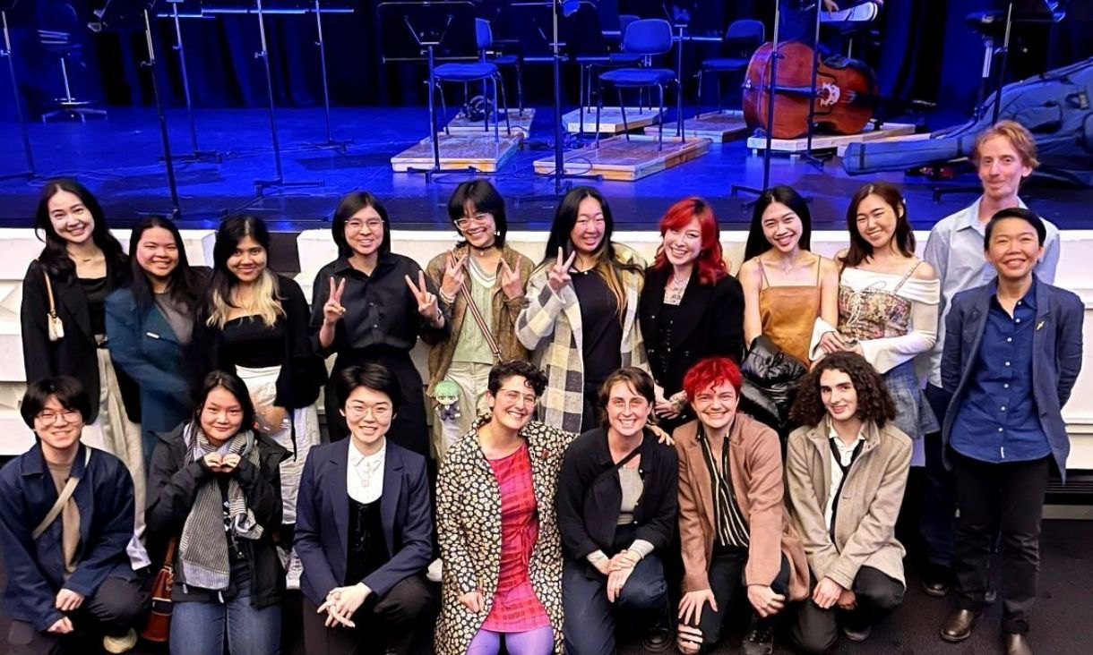 Large group of students posing in front of stage.