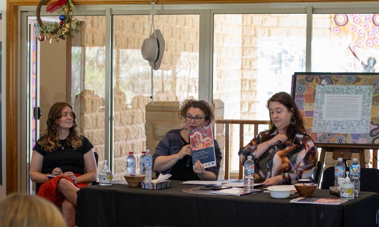 Panel members at table, with one member holding up report