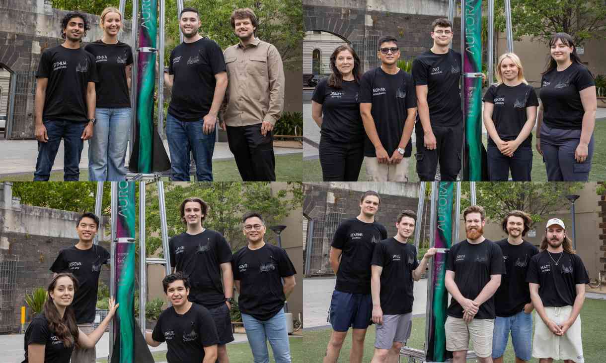 Students wearing uniform consisting of black t-shirts posing next to rocket.