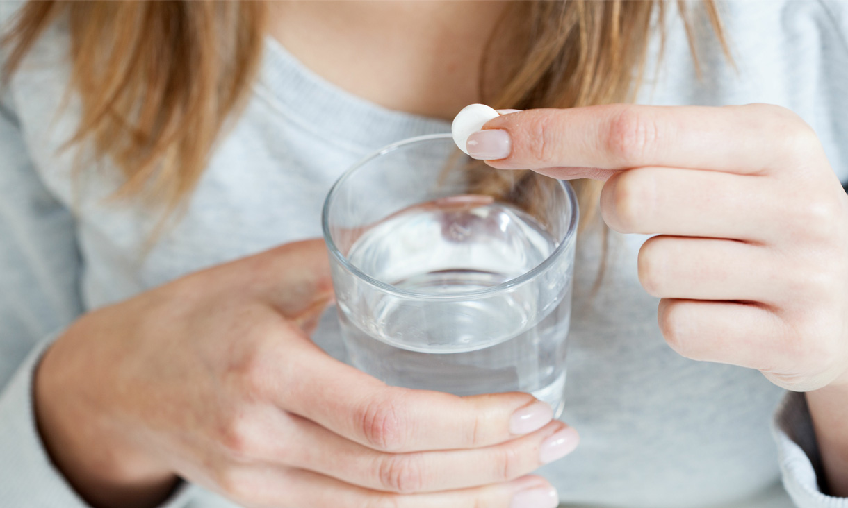 A person is holding an aspirin tablet and a glass of water. Credit: Photographee.eu, Adobe Stock