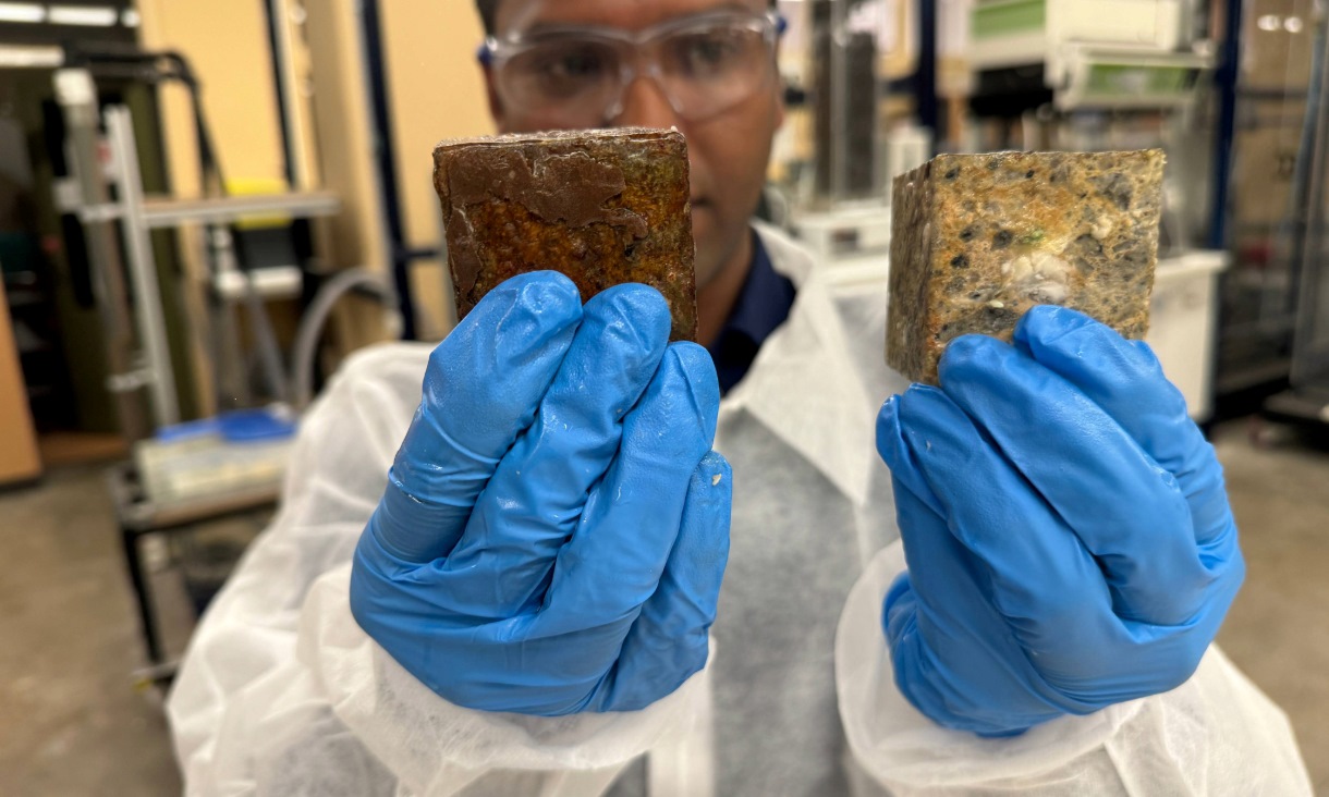 Dr Biplob Pramanik shows the difference between a concrete block coated with his team's anti-fatberg invention compared to a block without any coating after undergoing an experiment that mimicked a sewer environment under extreme conditions to speed up the fatberg formation process. The white coloured blobs on the uncoated block are a mixture of fat, oil and grease (FOG). Credit: Will Wright, RMIT University