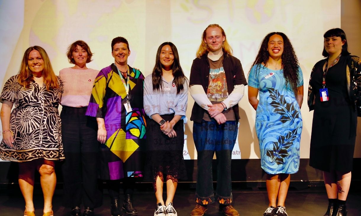 Group photo of panellists on stage in front of PowerPoint slide