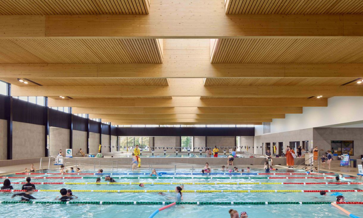 Indoor swimming pool with wood panel ceiling.