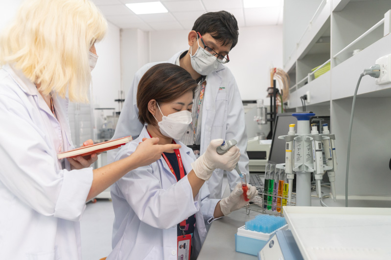 Three lab technicians in white coat and masks